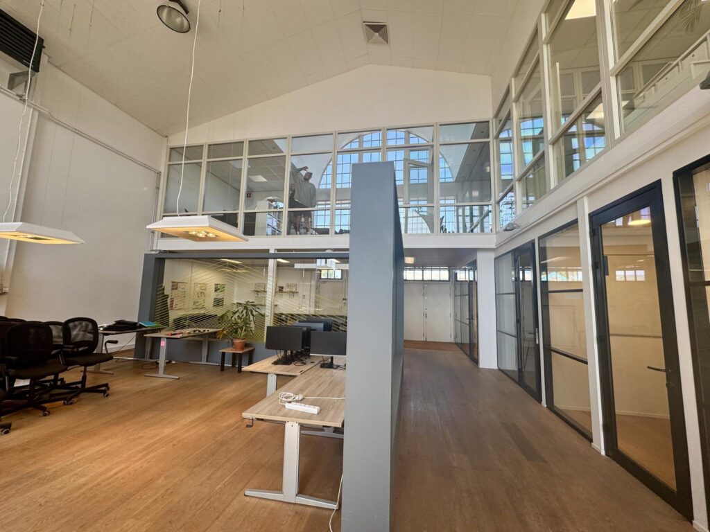 Modern kantoorinterieur aan het Gedempt Hamerkanaal met glazen wanden, houten vloer en open werkplekken.